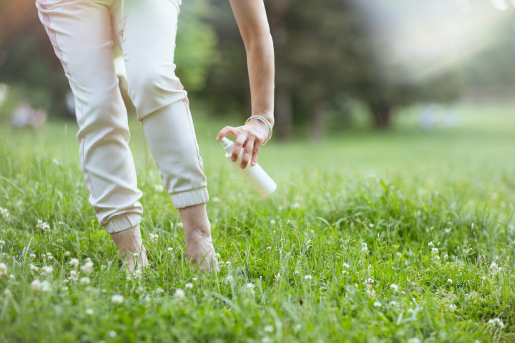 Femme avec un spray anti-acariens dans la pelouse naturelle