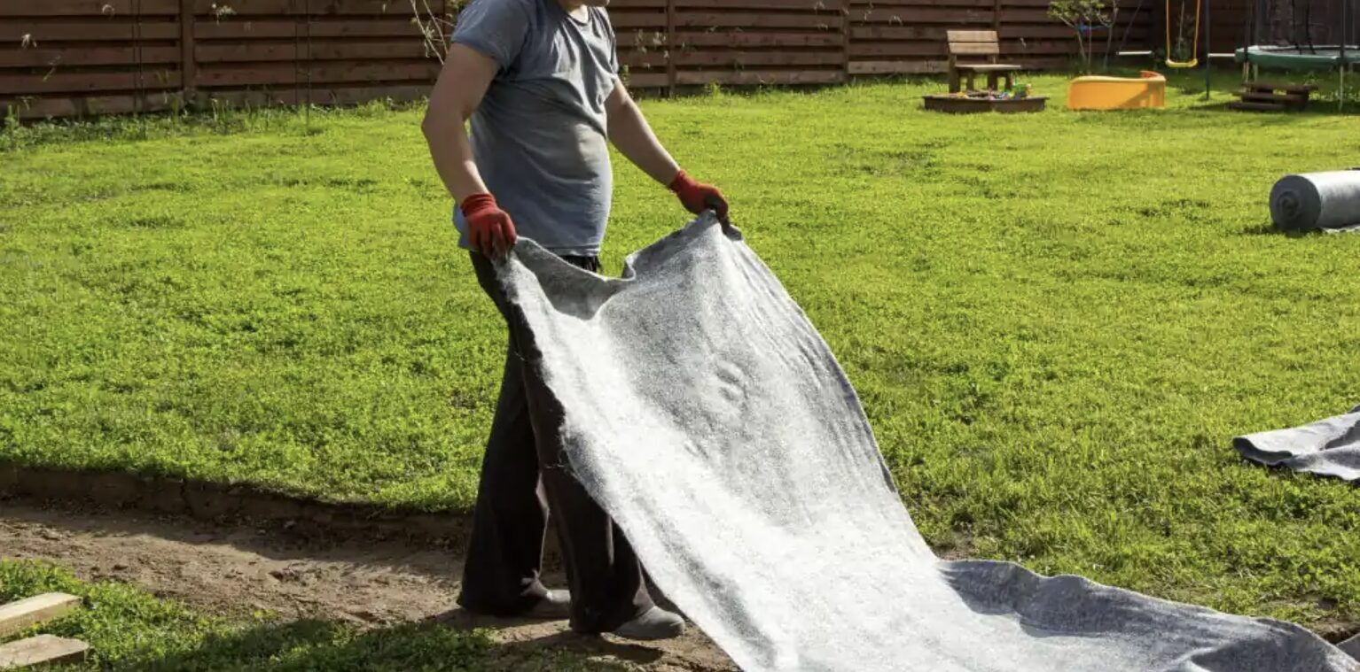 Pose d’un géotextile sous un gazon synthétique pour une meilleure stabilité et drainage.