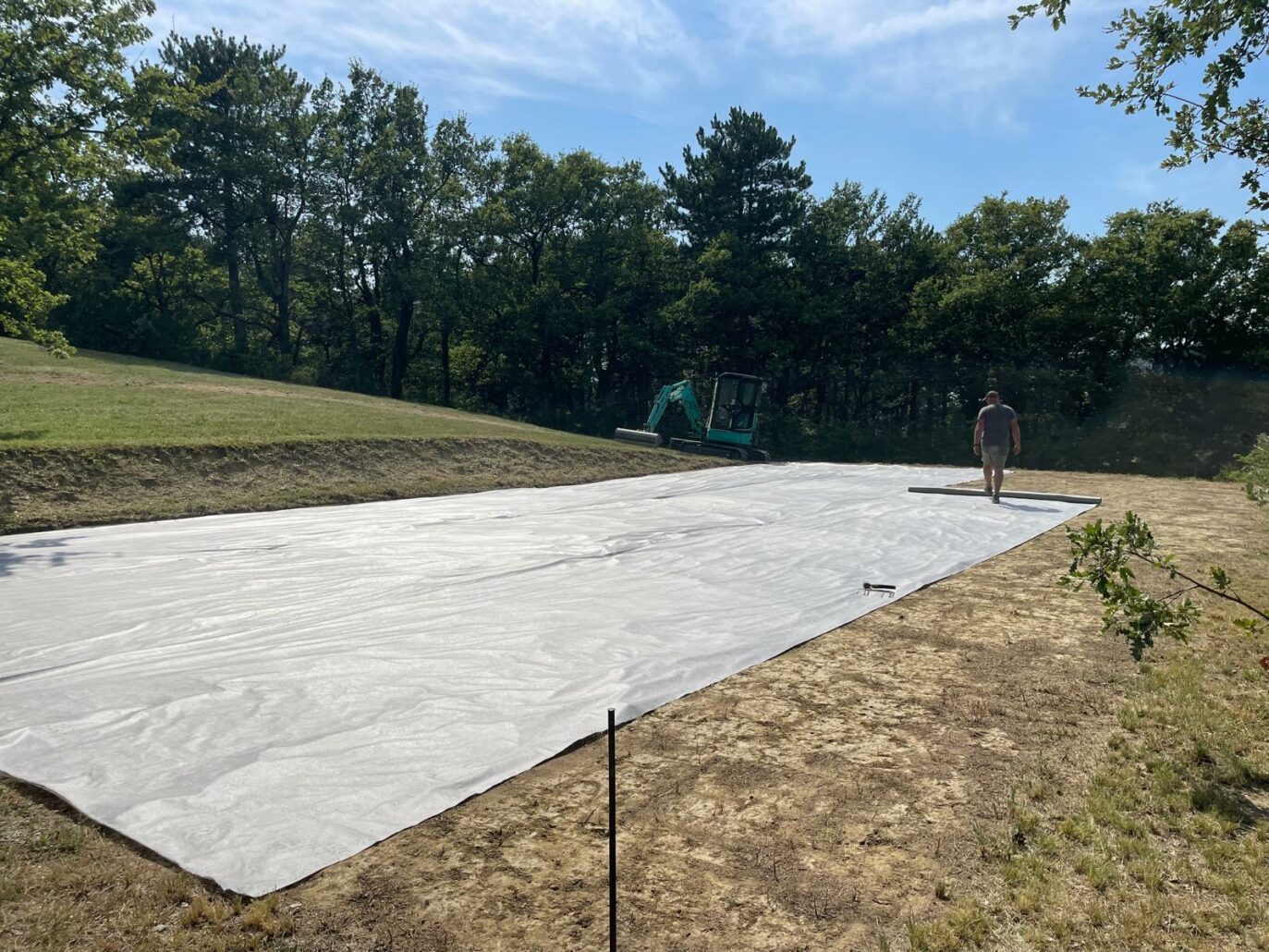 Pose d’un géotextile avant installation d’un gazon synthétique pour stabiliser le sol.